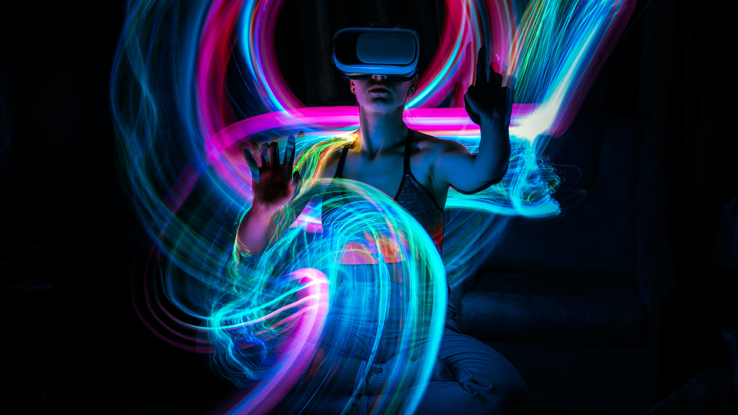 ViTeach-Konferenz 2025: Bild mit Frau und VR-Brille. Der Hintergrund ist schwarz und vor der Frau sind farbige Lichtstreifen zu sehen.